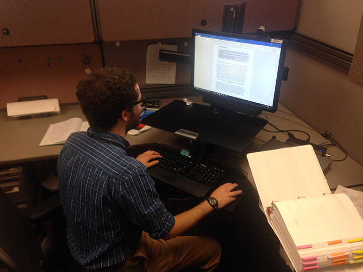 A man sitting at a desk looking at a computer screen. 