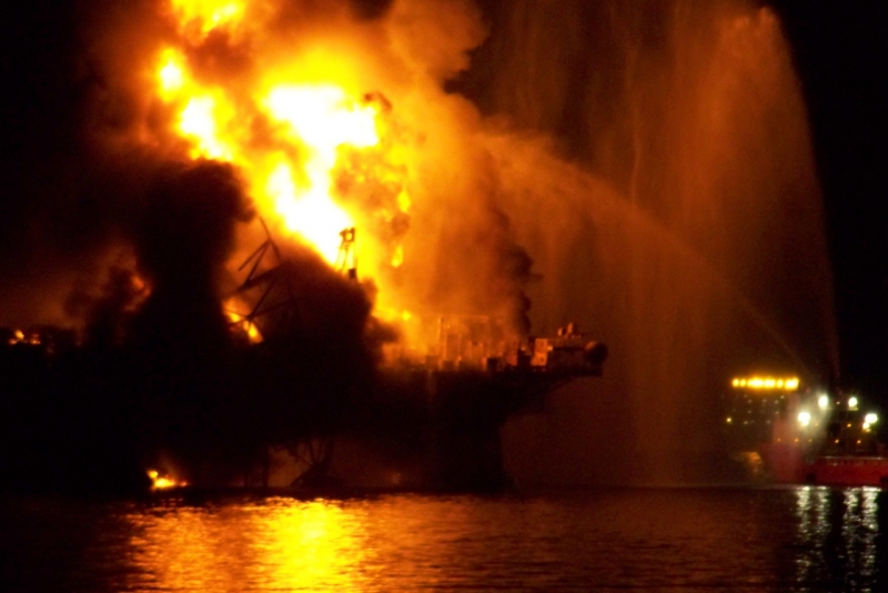 A dark and blurry image of an oil platform on fire.