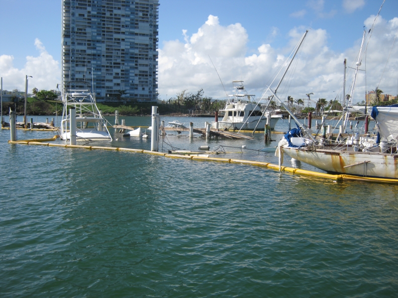 Several capsized vessels surrounded by pollution boom.