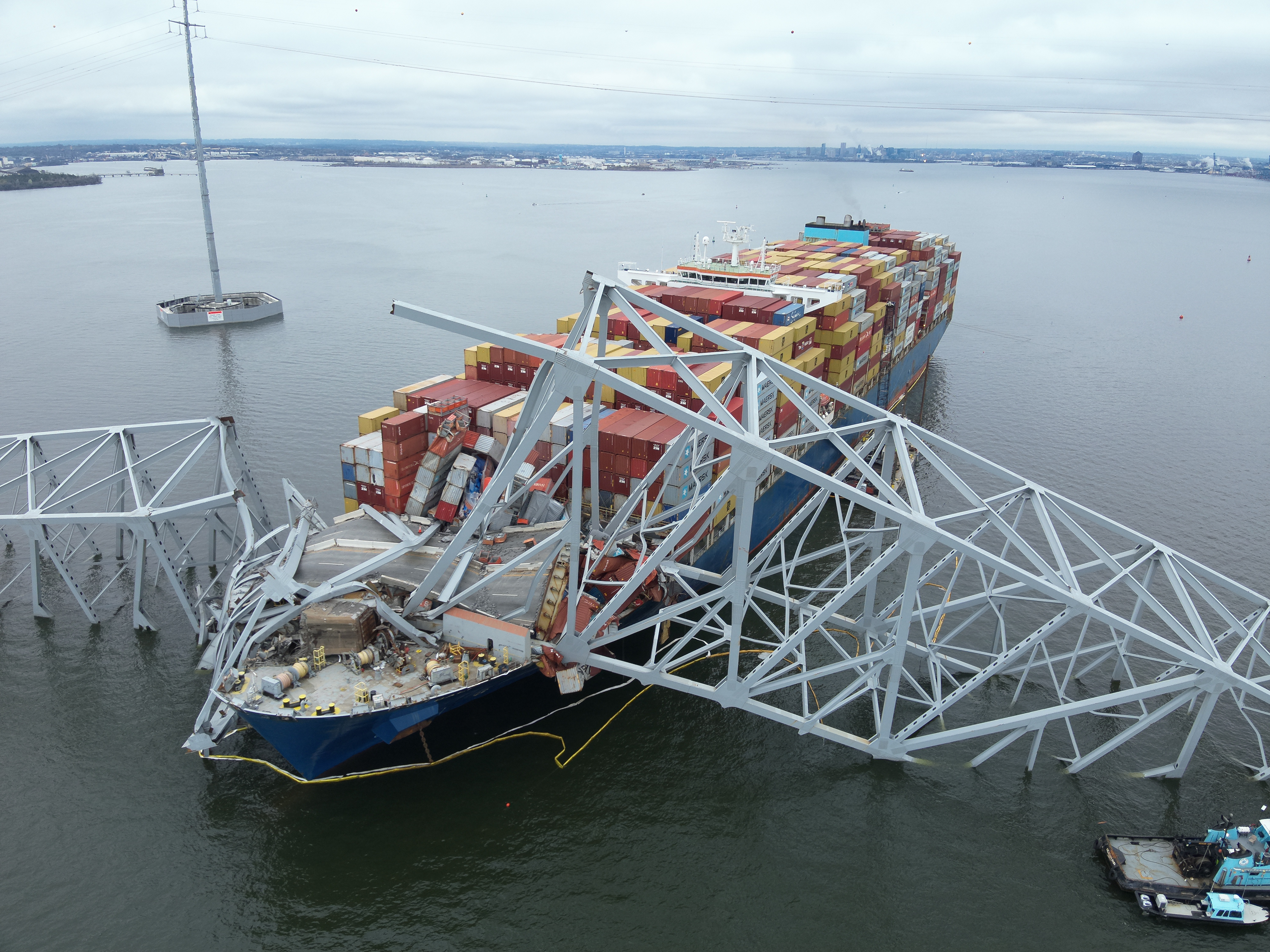 An aerial view of bridge section that lies across the bow of a large container ship after collapse. 