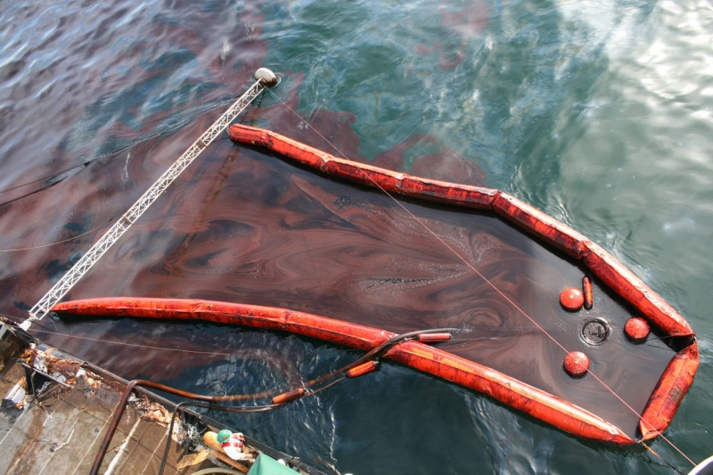 An oil skimmer surrounding a sheen in the water. 