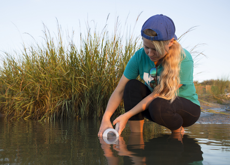 A woman collecting water from a body of water. 