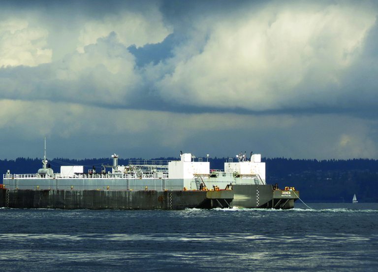 A vessel in water with dark storm clouds in the background. 