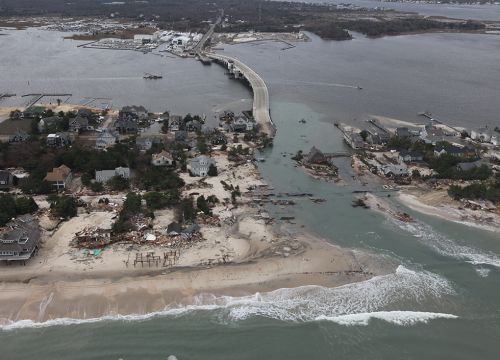 A damaged highway bridge on a flooded shoreline.