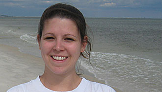 A portrait shot of a woman with a beach in the background. 