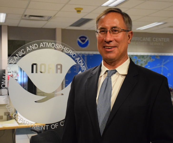 A man standing next to a NOAA logo. 