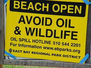 A sign warning people of oil on a beach.