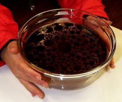 A bowl of liquid with a dark substance floating in it. 