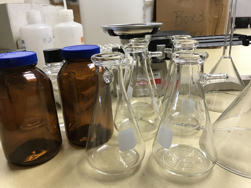 Beakers and jars sitting on a table. 
