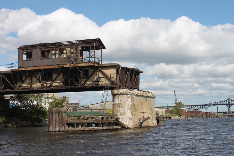 An old building falling apart on a bridge over a river. 