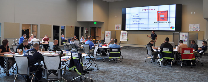 A large conference room with people sitting at round tables. 