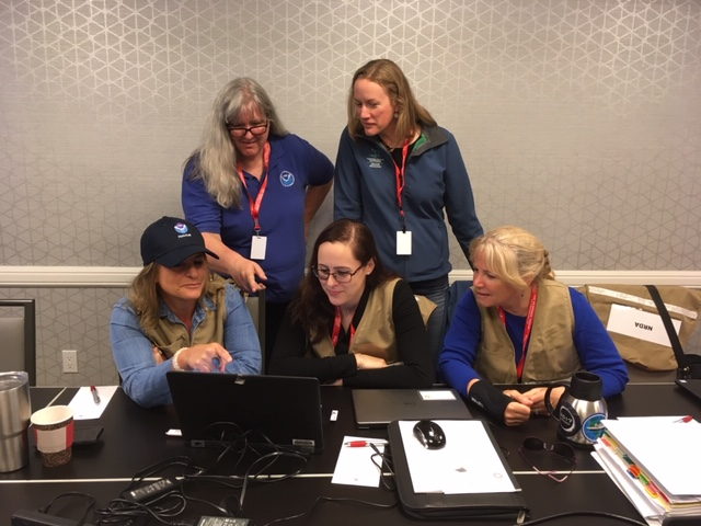 Five people standing at a desk.