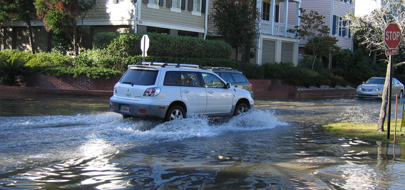 A car driving through a flooded street. 