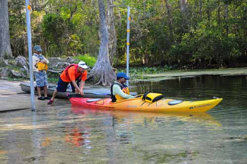 A group of people getting into kayaks. 