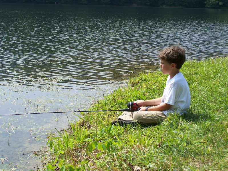 A young boy fishing on a river.