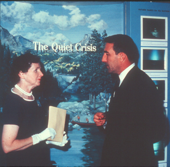 A woman holding a book talking to a man.