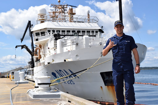 A person in uniform on a dock with a vessel in the background.