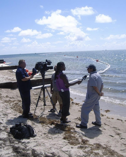 A tv crew interviews a person on a beach.