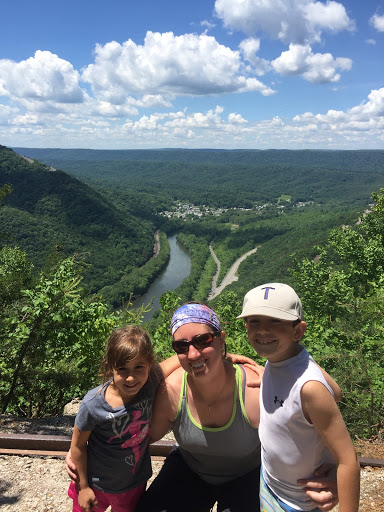 Three people smile for a picture taken at the top of a lush, green mountain in Pennsylvania.