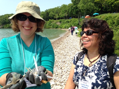 A woman holding out plastic debris in her hands with another woman next to her.