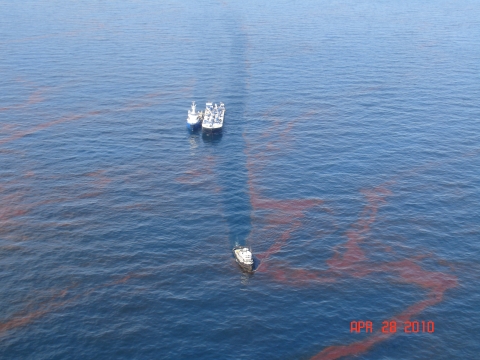 Vessels in water surrounded by an oil sheen. 