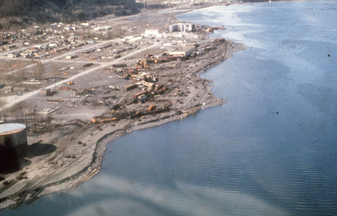 A waterfront shoreline in Alaska with damage caused by tsunami waves to a close by railroad yard.