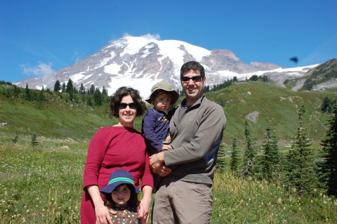 A woman a man and two kids with a snow-covered mountain in the background. 