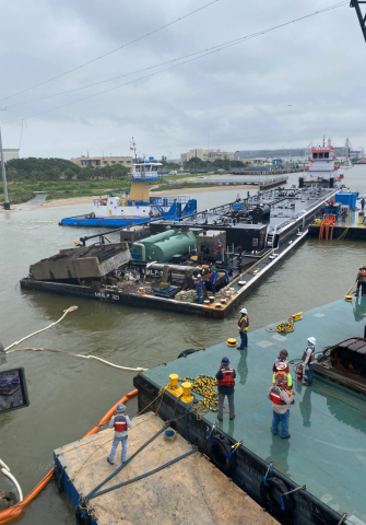 Response personnel standing near the removal of a barge.