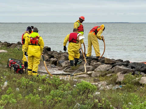 Responders clean oil off coastal rocks.