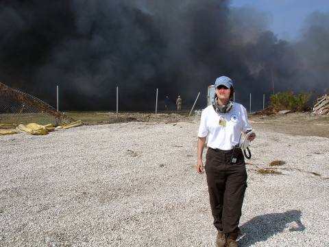 A woman walking forward with smoke billowing behind her. 