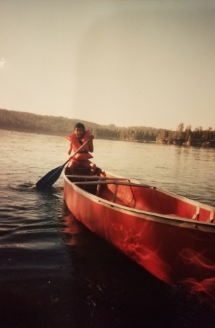 A kid canoeing on a lake.