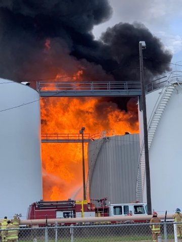 A fire erupting between several larger building structures.
