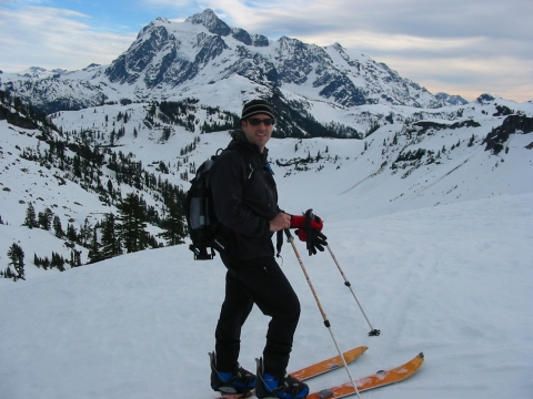 A man on skis with a snow-covered mountain landscape in the background. 