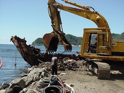 Large construction equipment tearing apart a derelict vessel. 
