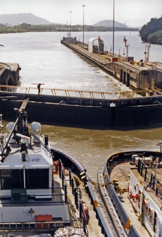 Two vessels wait behind a set of canal locks.