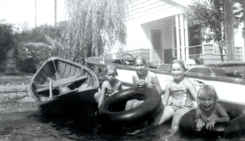 Four young girls with boats and inner tubes on beach.