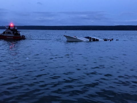 A small boat next to a partially sunken vessel.