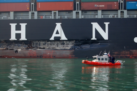 A close-up view of a smaller vessel in front of a container vessel. 