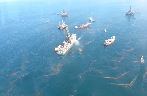 Vessels in water surrounded by an oil sheen. 