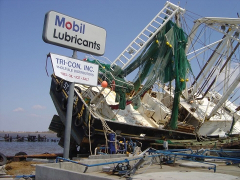 A displaced vessel in a gas station parking lot near the shore.