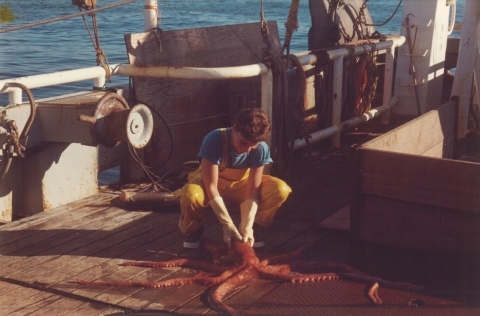 A woman holding an octopus on a boat.