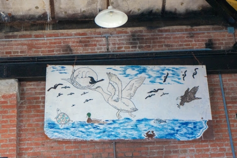 A piece of art showing a river with various marine and wildlife in and above it.