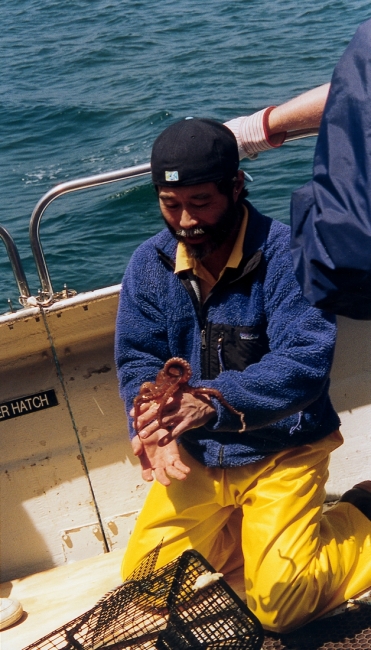 A man on a boat holding an octopus.