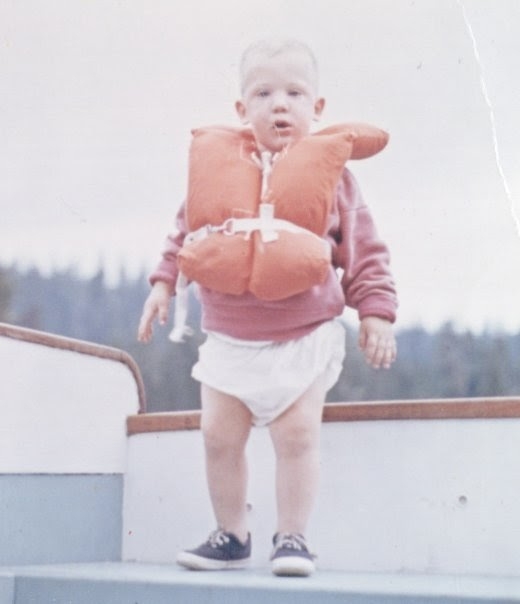 A child in a life jacket on a boat.