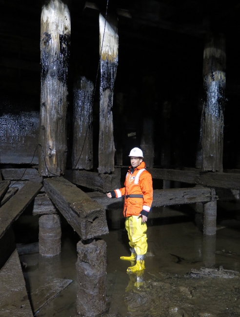 Man standing next to oiled pilings.