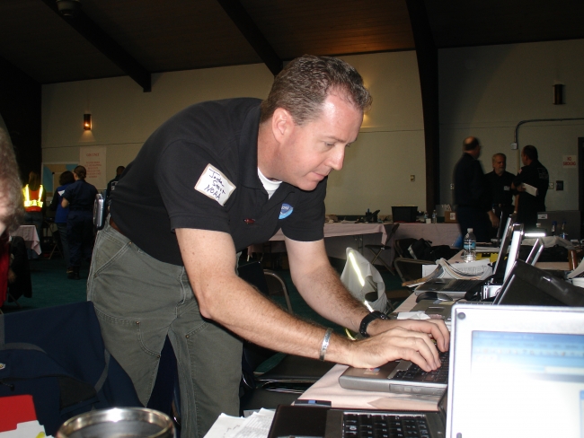 A man leaning over a laptop typing. 