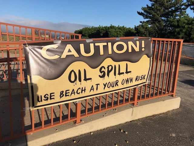 A sign reading "Caution: Oil Spill." 
