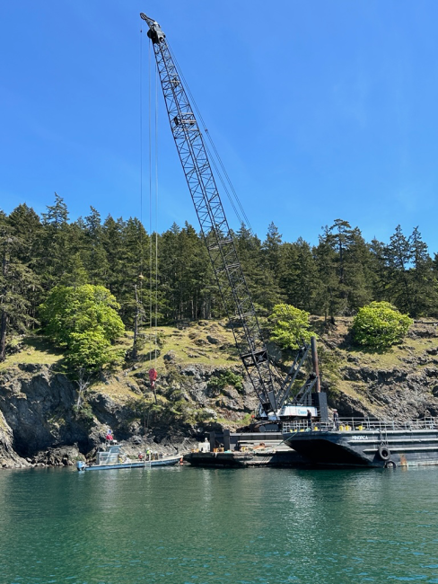 A crane secured on a barge prepares to lift a sunken vessel.