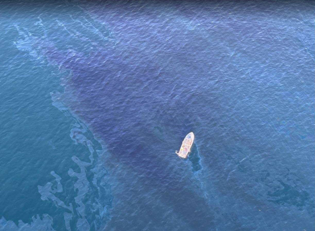 Aerial view of a vessel floating amongst a mystery sheen in the open ocean.