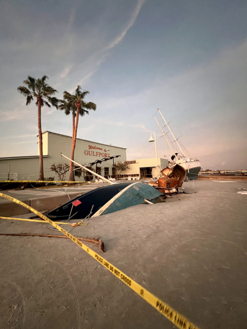 Damaged boats pushed ashore a Florida coastline surrounded by caution tape.